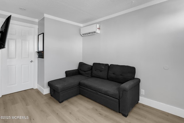 living room with a wall mounted AC, light wood-type flooring, baseboards, a textured ceiling, and ornamental molding