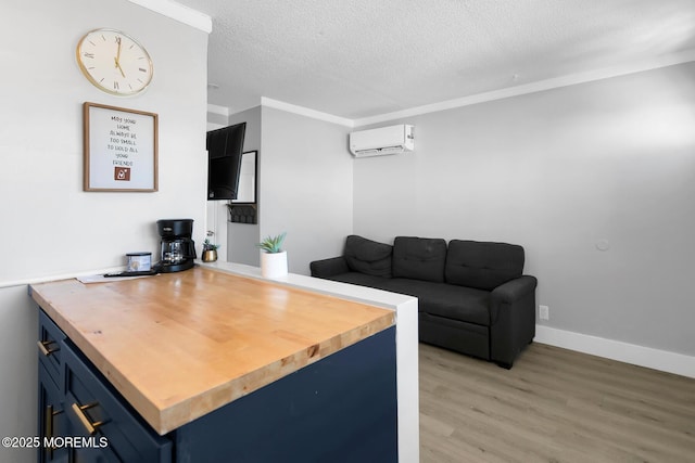 office with light wood finished floors, a wall mounted air conditioner, a textured ceiling, ornamental molding, and baseboards