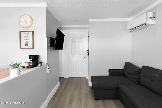 living room with a wall unit AC, light wood-type flooring, a textured ceiling, and baseboards