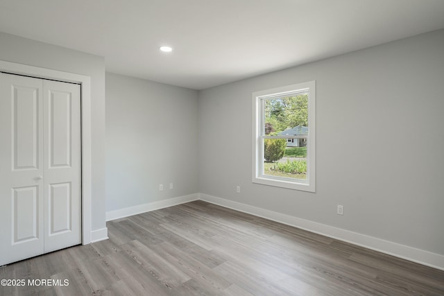 unfurnished bedroom with baseboards, recessed lighting, a closet, and wood finished floors