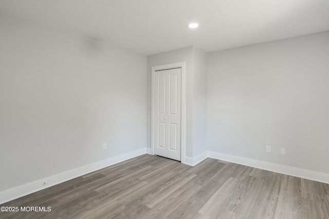 unfurnished room with wood finished floors, baseboards, and recessed lighting