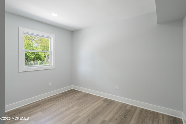 empty room featuring light wood finished floors, baseboards, and recessed lighting
