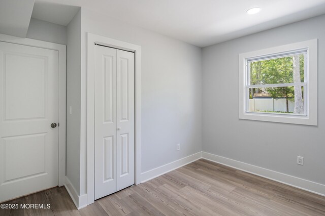 unfurnished bedroom featuring light wood finished floors, baseboards, a closet, and recessed lighting