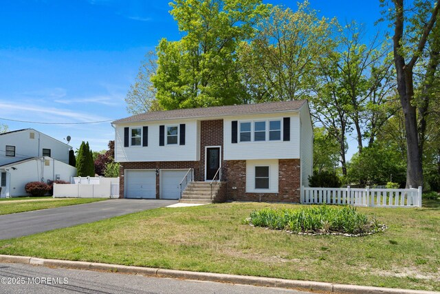 split foyer home featuring brick siding, driveway, and an attached garage