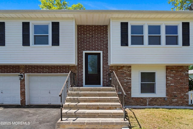 raised ranch with brick siding, driveway, and an attached garage