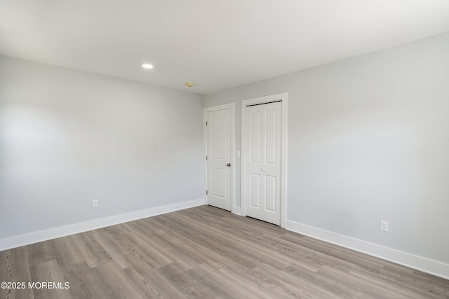 unfurnished bedroom with baseboards, recessed lighting, light wood-style flooring, and a closet