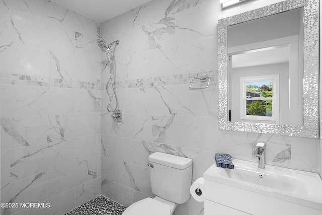 full bath with tile walls, tiled shower, toilet, and vanity