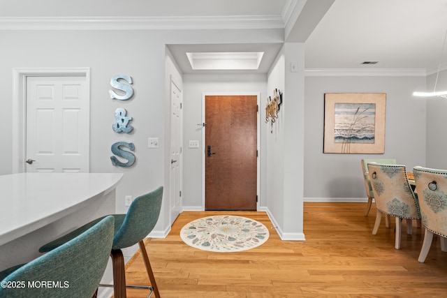 entryway featuring baseboards, light wood-style flooring, and ornamental molding
