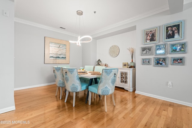 dining room featuring ornamental molding, light wood-style floors, baseboards, and a chandelier