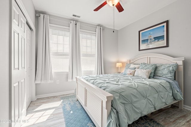 bedroom featuring light wood finished floors, multiple windows, and baseboards