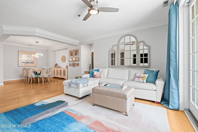 living area with crown molding, wood finished floors, ceiling fan, a chandelier, and baseboards