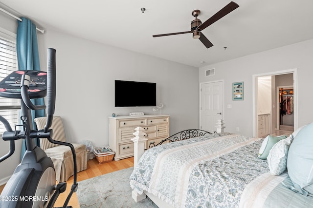 bedroom with wood finished floors, ceiling fan, and a walk in closet