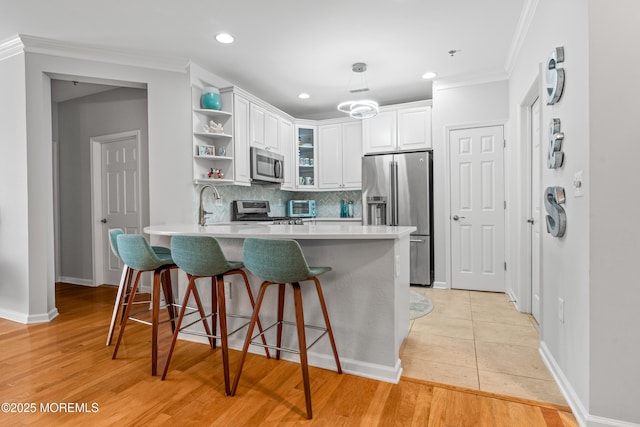 kitchen featuring appliances with stainless steel finishes, a peninsula, open shelves, decorative backsplash, and a kitchen breakfast bar