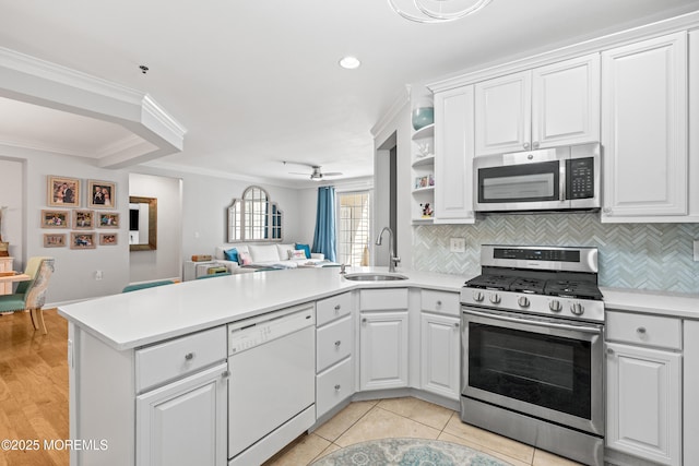 kitchen featuring stainless steel appliances, a sink, a peninsula, open floor plan, and light countertops