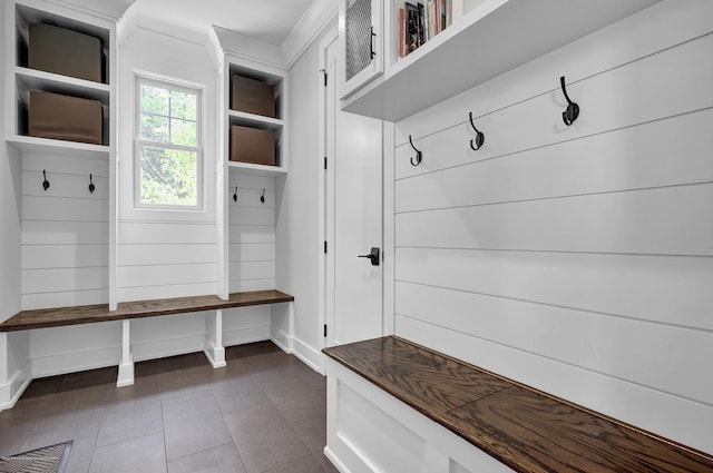 mudroom with dark tile patterned flooring and baseboards