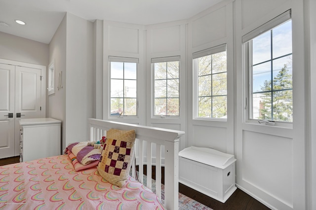 bedroom with multiple windows, dark wood-style floors, a decorative wall, and recessed lighting