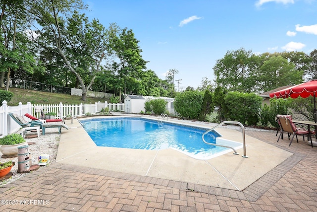 view of pool with a patio area, a fenced backyard, an outdoor structure, and a storage shed