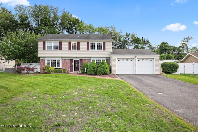 colonial home with a garage, asphalt driveway, and brick siding