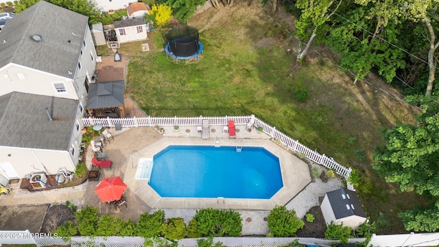 view of pool with a trampoline and a fenced backyard
