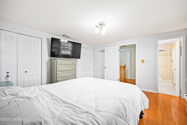 bedroom featuring two closets, light wood finished floors, baseboards, and ensuite bathroom