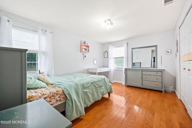 bedroom featuring light wood finished floors, baseboards, and a closet