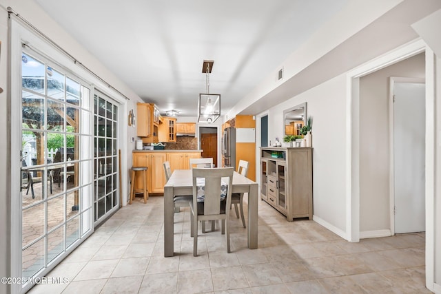 dining space featuring light tile patterned floors and baseboards