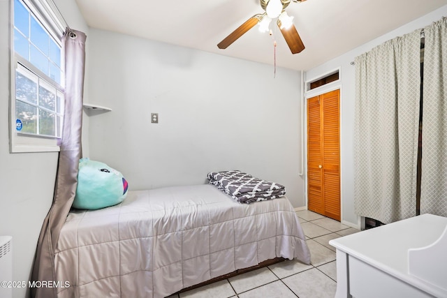 bedroom featuring light tile patterned flooring, a closet, and a ceiling fan
