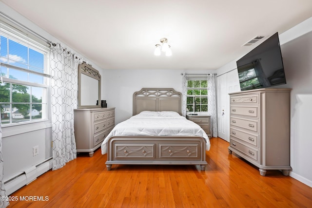 bedroom with baseboard heating and light wood finished floors