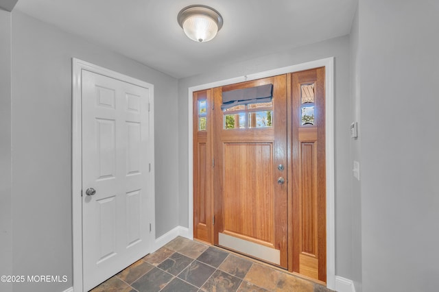 entrance foyer featuring baseboards and dark stone finish floors