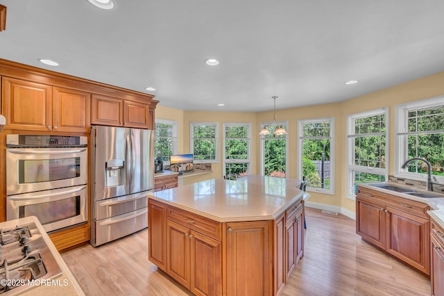 kitchen featuring stainless steel appliances, a sink, light countertops, healthy amount of natural light, and recessed lighting