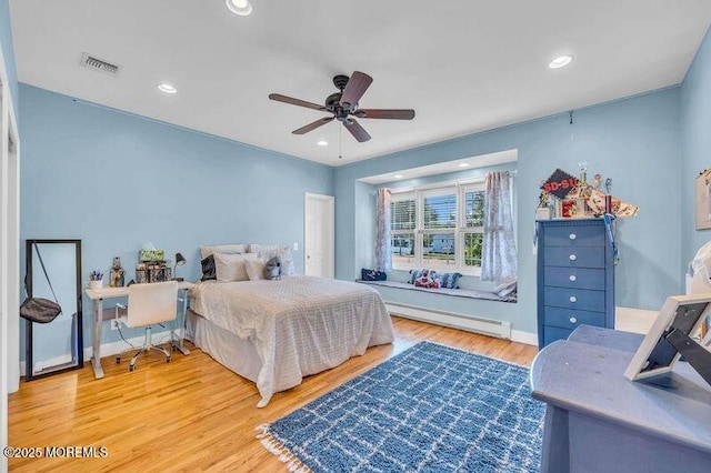 bedroom with a baseboard heating unit, wood finished floors, recessed lighting, a ceiling fan, and baseboards
