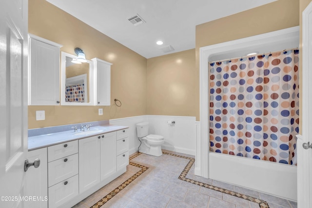 full bathroom with toilet, vanity, shower / bathtub combination with curtain, a wainscoted wall, and tile patterned floors