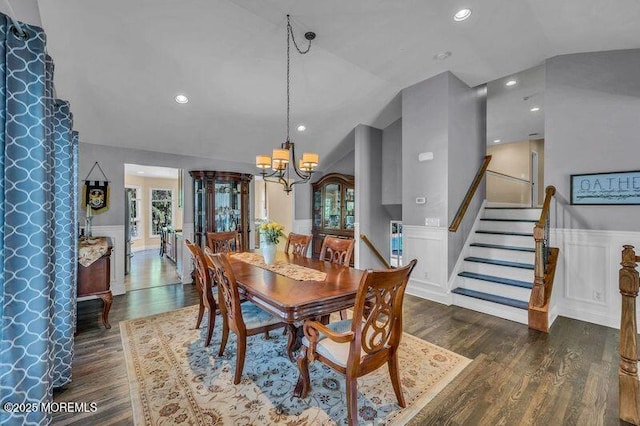 dining space with vaulted ceiling, dark wood-style floors, a chandelier, a wainscoted wall, and a decorative wall