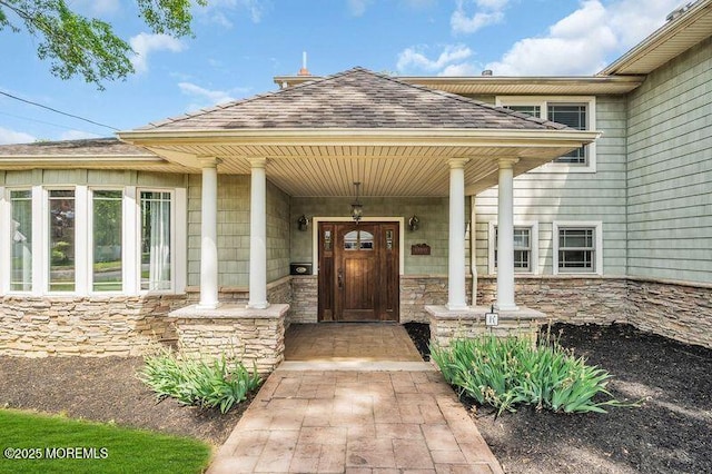 view of exterior entry with stone siding and covered porch