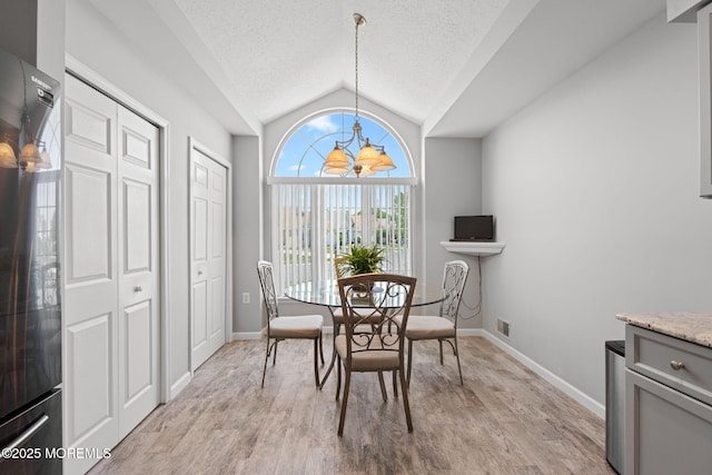 dining space featuring lofted ceiling, light wood finished floors, baseboards, a textured ceiling, and a chandelier