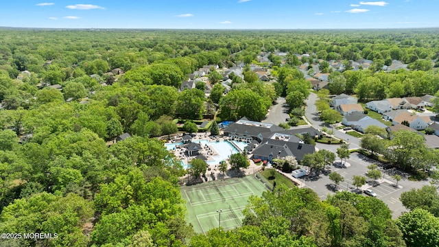 drone / aerial view of a forest and a pool area