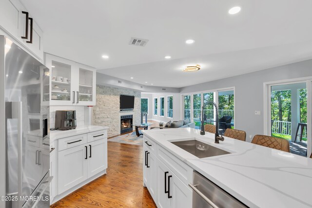 401 Overlook Dr, Neptune Township, NJ 07753 - kitchen with stainless steel fridge, a sink, a stone fireplace, light wood-type flooring, and glass insert cabinets