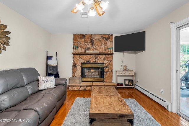 6 Blanche Dr, New Egypt, NJ 08533 - living room with a baseboard heating unit, ceiling fan, a stone fireplace, and wood finished floors