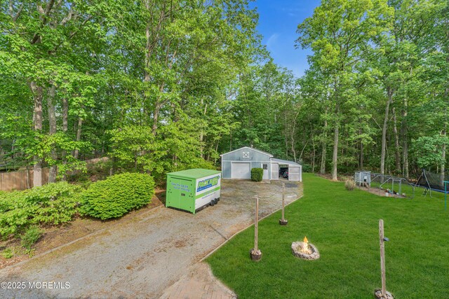 6 Blanche Dr, New Egypt, NJ 08533 - view of grassy yard featuring a detached garage, an outdoor structure, driveway, and a fire pit