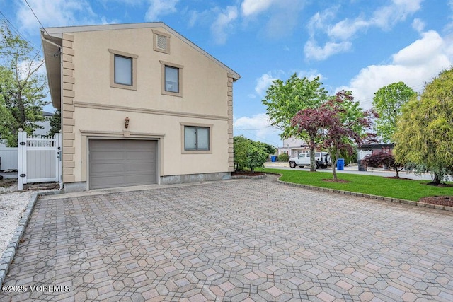 251 Genes Dr, Toms River, NJ 08753 - view of side of property with stucco siding, decorative driveway, an attached garage, and fence