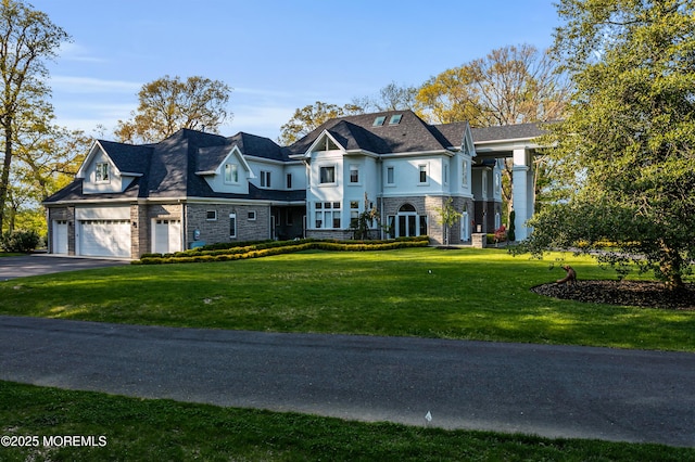 french country home featuring driveway, a front yard, a garage, and stucco siding
