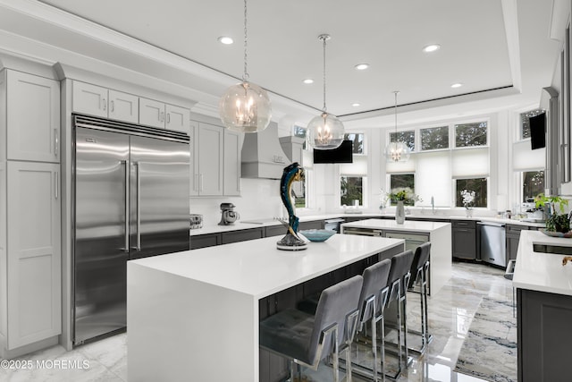 kitchen with stainless steel appliances, a center island, light countertops, recessed lighting, and light marble finish floors