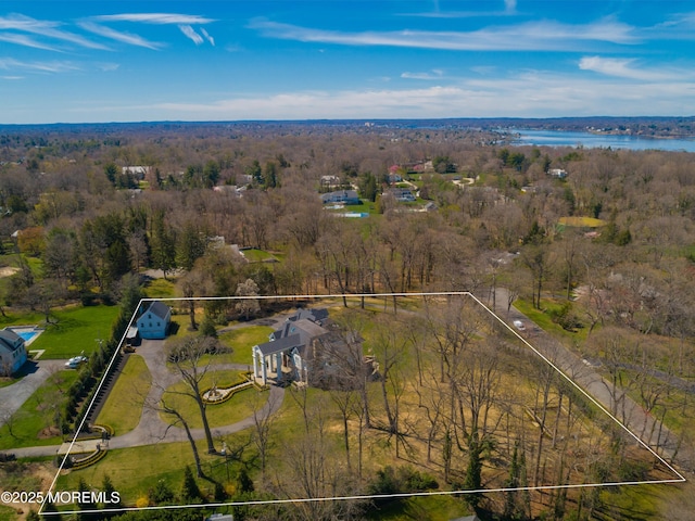 view of property location featuring property parcel outlined, a forest, and a nearby body of water
