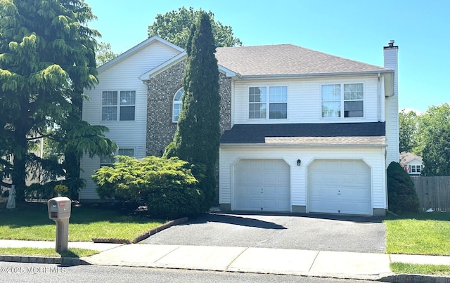 traditional-style home with a garage, asphalt driveway, a chimney, and a front lawn