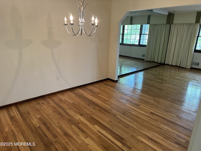 697 Vaughn Ave, Toms River, NJ 08753 - unfurnished dining area with a chandelier, arched walkways, hardwood / wood-style floors, and baseboards