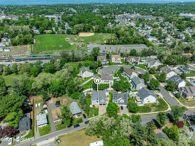aerial view of property's location featuring a tree filled landscape and nearby suburban area