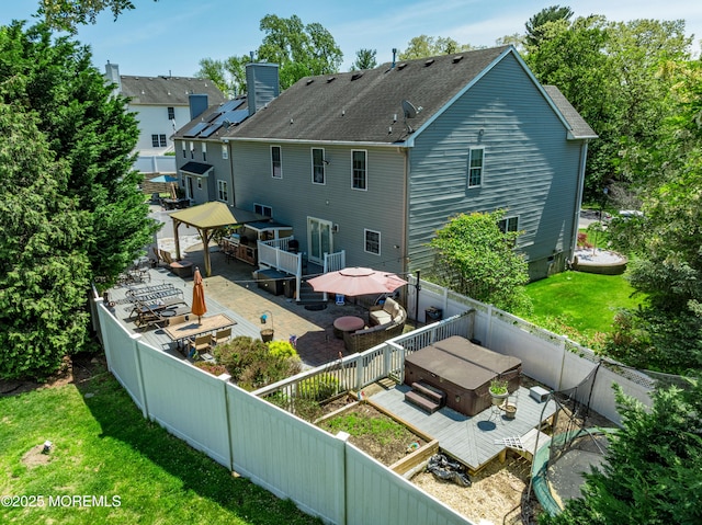 back of property with a gazebo, a wooden deck, a chimney, outdoor dining space, and roof with shingles