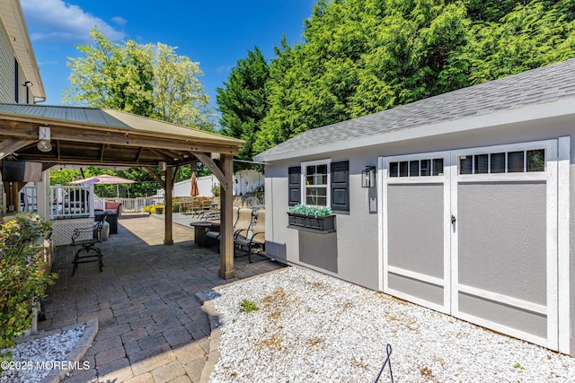 view of patio / terrace with a gazebo, an outdoor structure, fence, and a storage unit
