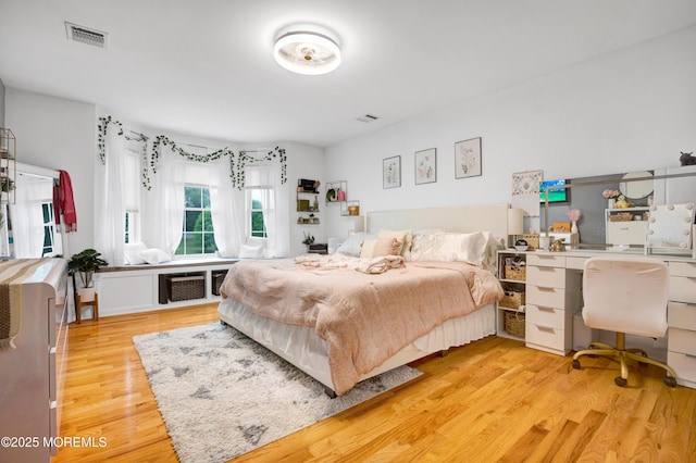bedroom with wood finished floors and an office area