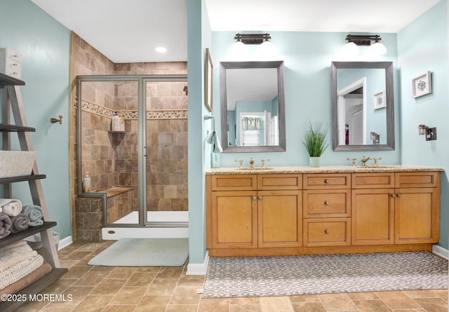 bathroom with baseboards, a shower stall, and double vanity